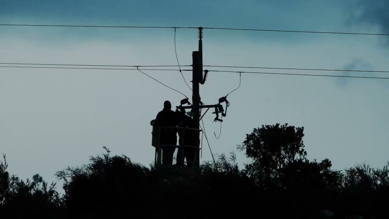 Utility lineworkers repairing power lines at dusk